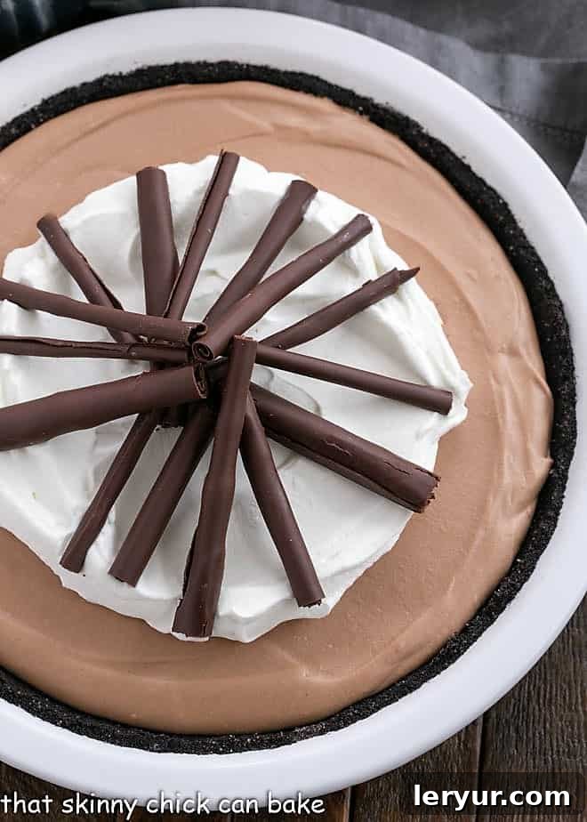 Overhead view of Candy Bar Pie garnished with chocolate and whipped cream in a white pie plate.