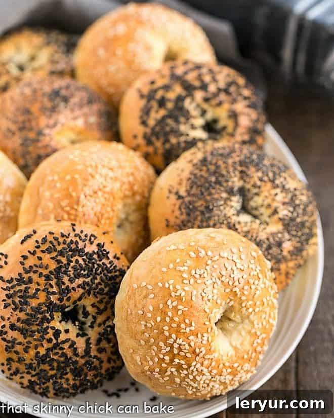 A selection of freshly baked homemade bagels arranged neatly on a white oval serving tray, ready to be enjoyed with various spreads.