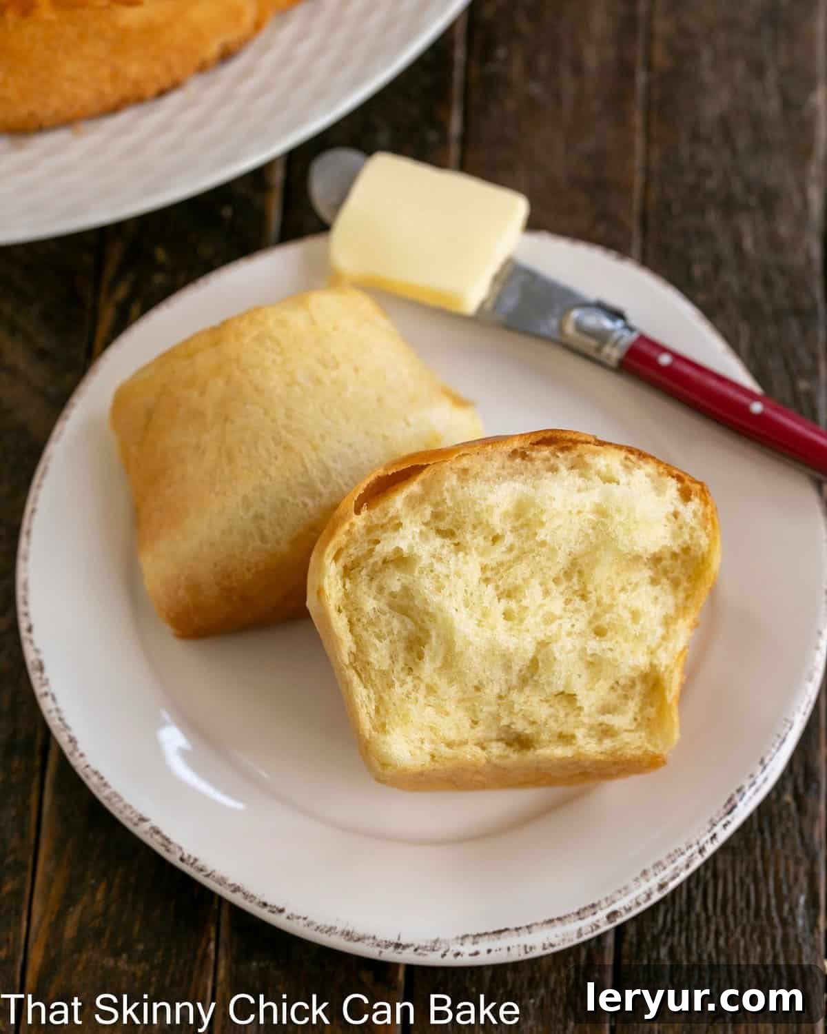 Fluffy Japanese Milk Bread 3 A Japanese Milk Bread Bun torn in half on a small white plate with a red butter knife.