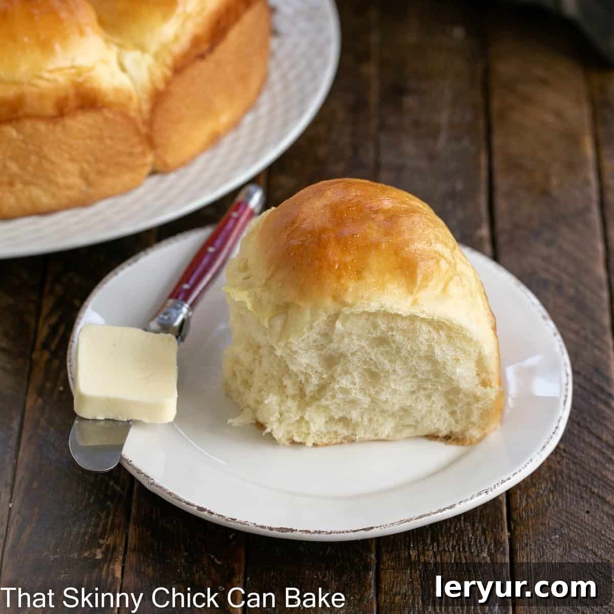 Fluffy Japanese Milk Bread 4 One Japanese Milk Bread Roll on a white plate with a red handled knife with a pat of butter.