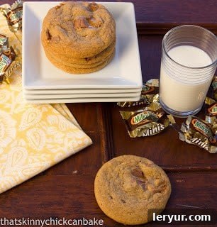 A stack of Milky Way Cookies artfully arranged on white serving plates, with empty candy wrappers and a refreshing glass of milk nearby, creating an inviting dessert scene.