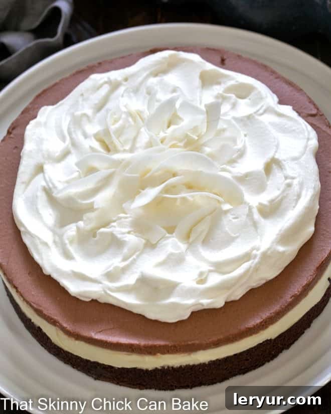 Close overhead view of a multi-layered brownie coconut cream cake on a white plate, showcasing its distinct textures and garnishes.