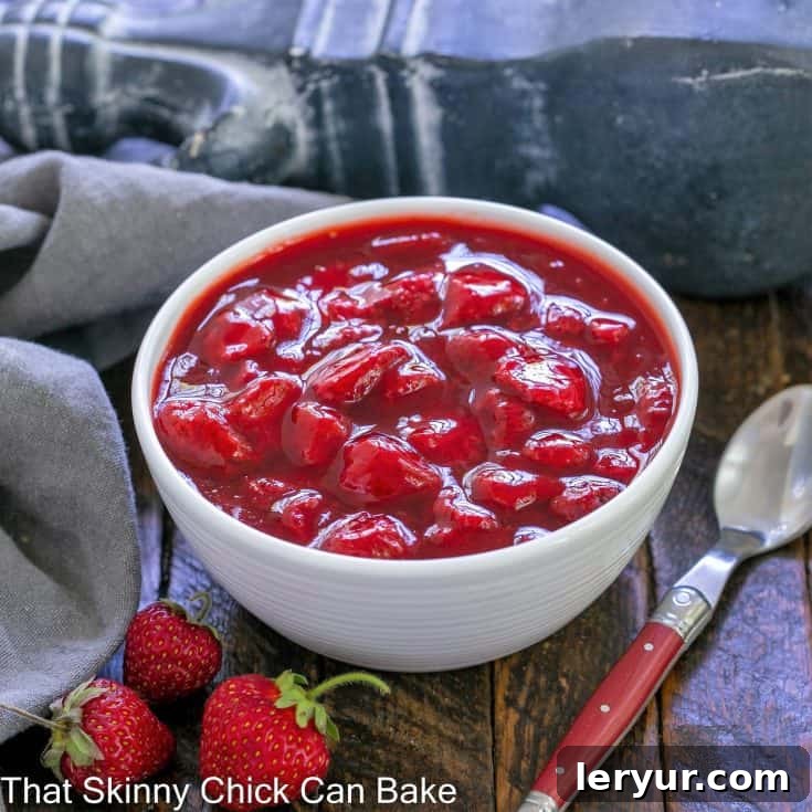 Fresh strawberry compote in a white bowl with a red handle spoon to the side