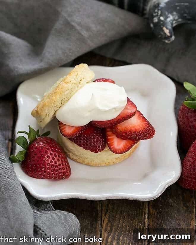 Classic Homemade Strawberry Shortcakes on a square white plate, garnished with a fresh strawberry half.