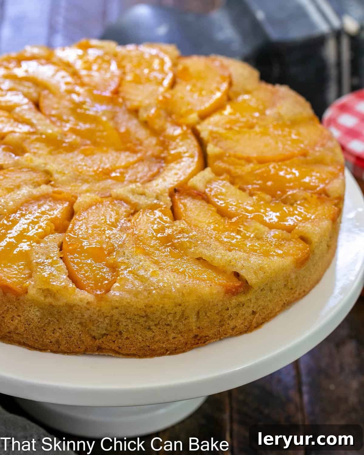 Caramelized Peach Flip Cake 5 A whole peach upside down cake on a white ceramic cake stand, ready to be served.