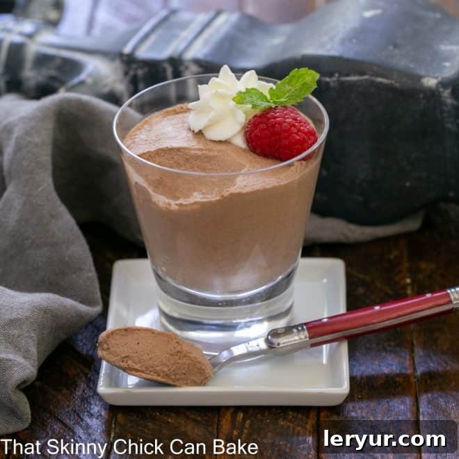 A serving of chocolate mousse in a glass with a spoonful removed on a red handled fork