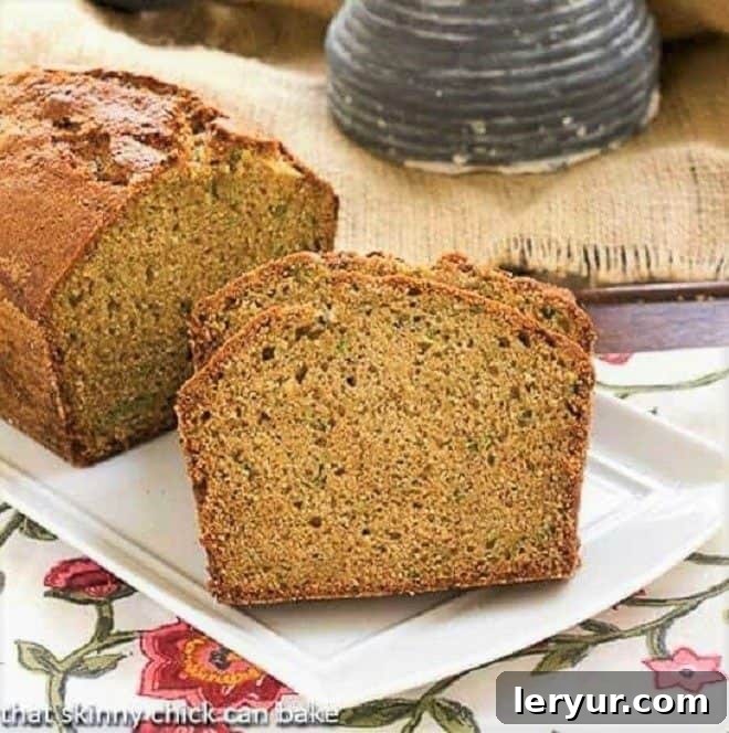 Sugar Crusted Zucchini Bread - A classic zucchini bread recipe with a sweet sugar crust Two loaves of Sugar Crusted Zucchini Bread, one whole and one sliced, on a white tray, showcasing its golden-brown crust and moist interior.