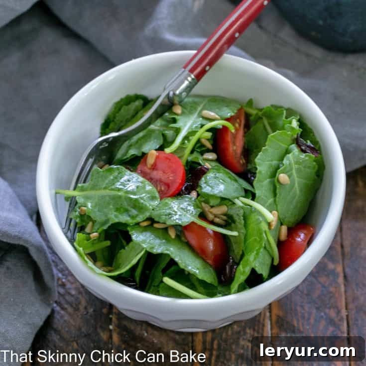 Overhead view of a small salad bowl filled with kale salad with a red handle fork.