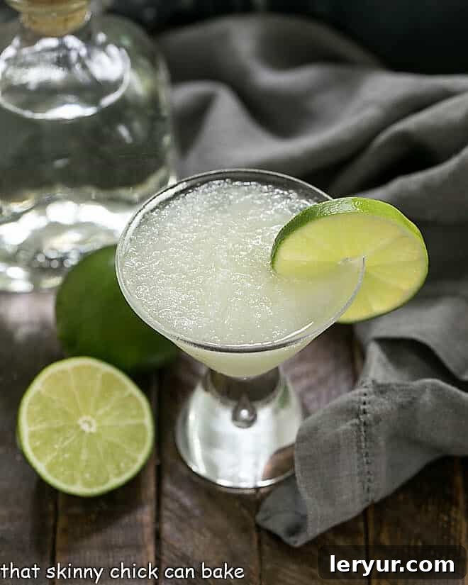 Easy 3-Ingredient Beer Margaritas with a lime garnish and tequila and limes in the background, set for a party.