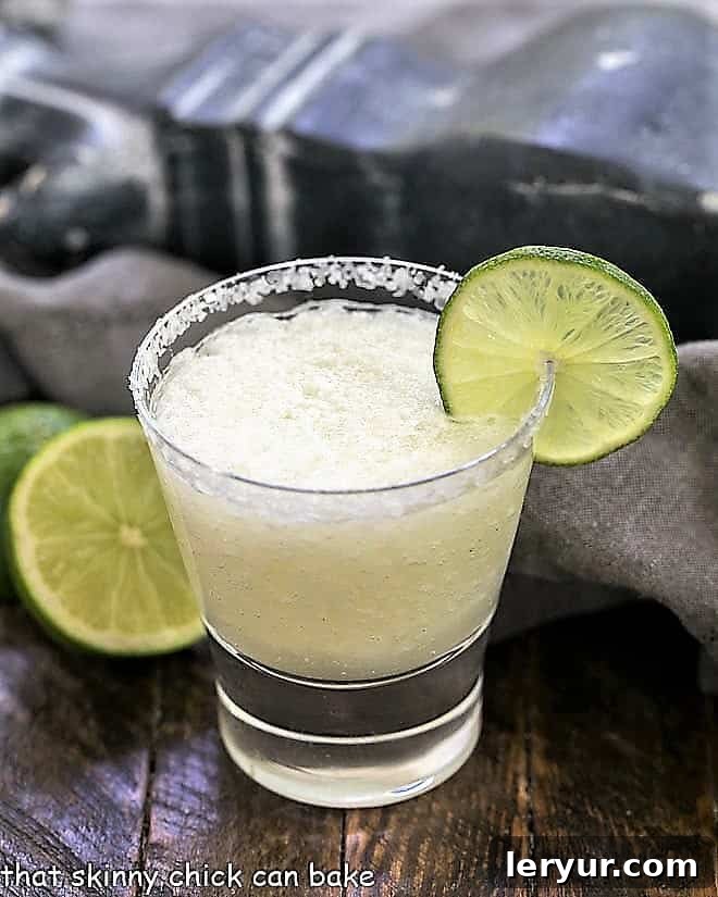 A beer margarita in a high ball glass with a salted rim and thin lime slice garnish, showcasing its refreshing appeal.