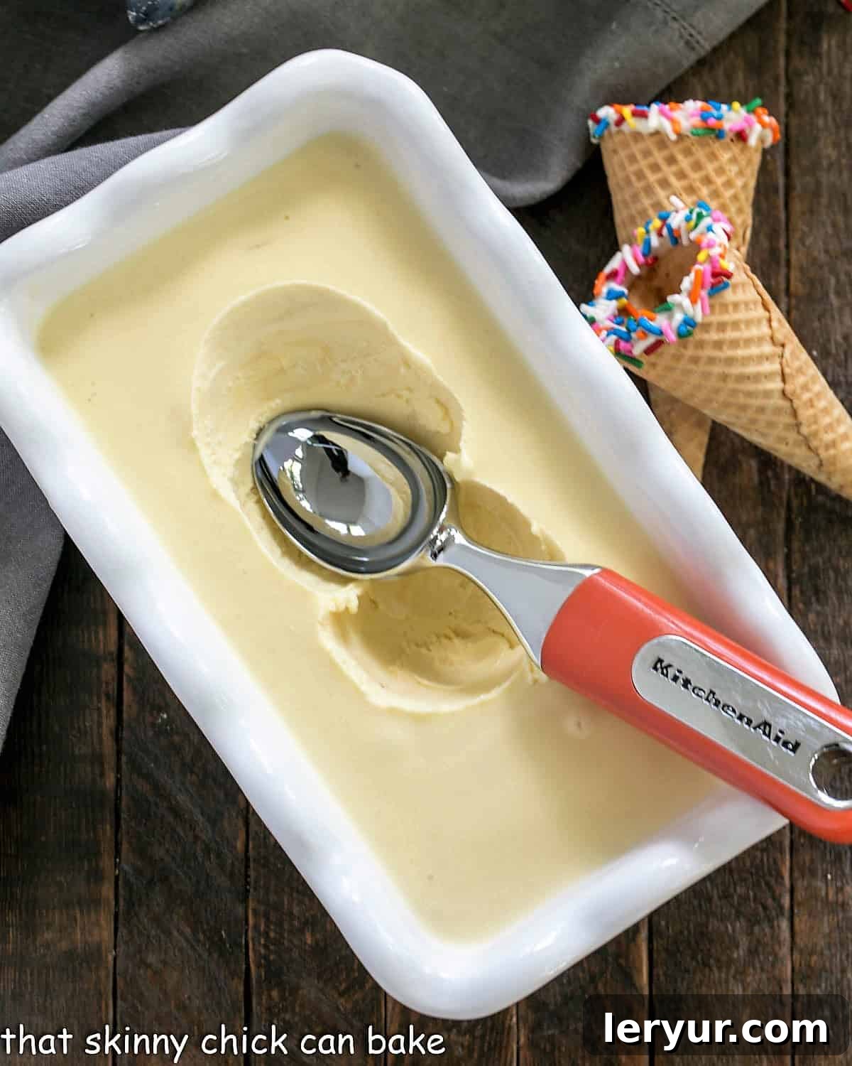 Homemade Cake Batter Ice Cream - A rich, celebratory vanilla ice cream infused with the delicious flavor of dry cake mix, perfect for any special occasion. Smooth, creamy Cake Batter Ice Cream resting in a freezer-safe dish, accompanied by an ice cream scooper, ready for future indulgence.