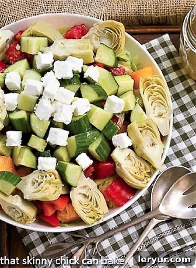 A vibrant Greek Salad with Feta, brimming with colorful vegetables and creamy feta cubes, served in a white bowl on a green and white checkered napkin.