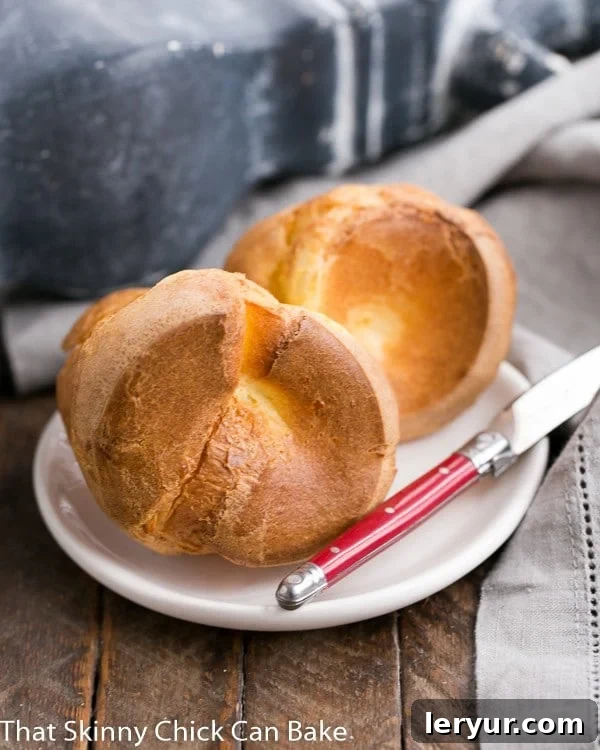 Fluffy Popover Perfection 2 A cluster of golden-brown perfect popovers arranged elegantly on an oval white plate, showcasing their impressive puff.