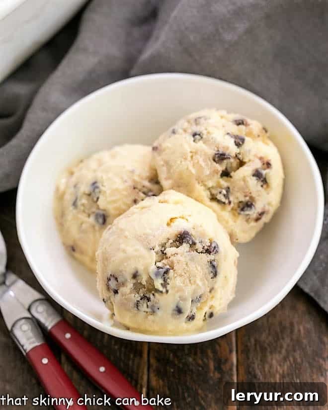 Overhead view of 3 scoops of cookie dough ice cream in a white bowl.