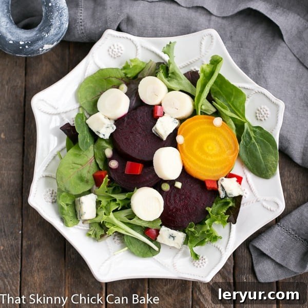 A close-up shot of Beet Salad with Blue Cheese and Hearts of Palm arranged artfully on a hexagonal white salad plate, highlighting its fresh components.