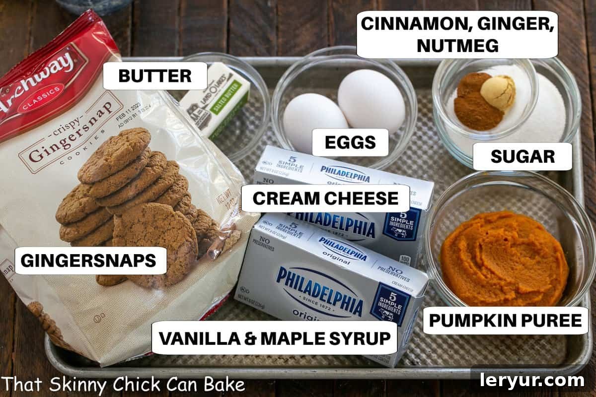 A comprehensive flat lay of labeled ingredients, including gingersnap cookies, cream cheese, pumpkin puree, and various spices, meticulously arranged on a metal sheet pan, ready for preparing the mini pumpkin cheesecakes.