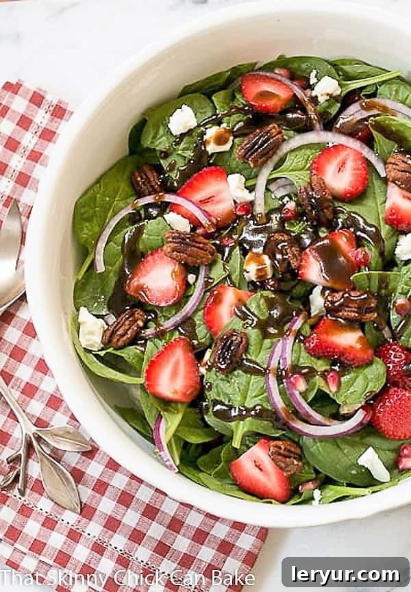 Spinach, Strawberry, Pomegranate, Feta Salad with the BEST balsamic vinaigrette! A vibrant Spinach, Strawberry, Pomegranate, Feta Salad generously drizzled with a homemade balsamic vinaigrette, served in a pristine white ceramic bowl.