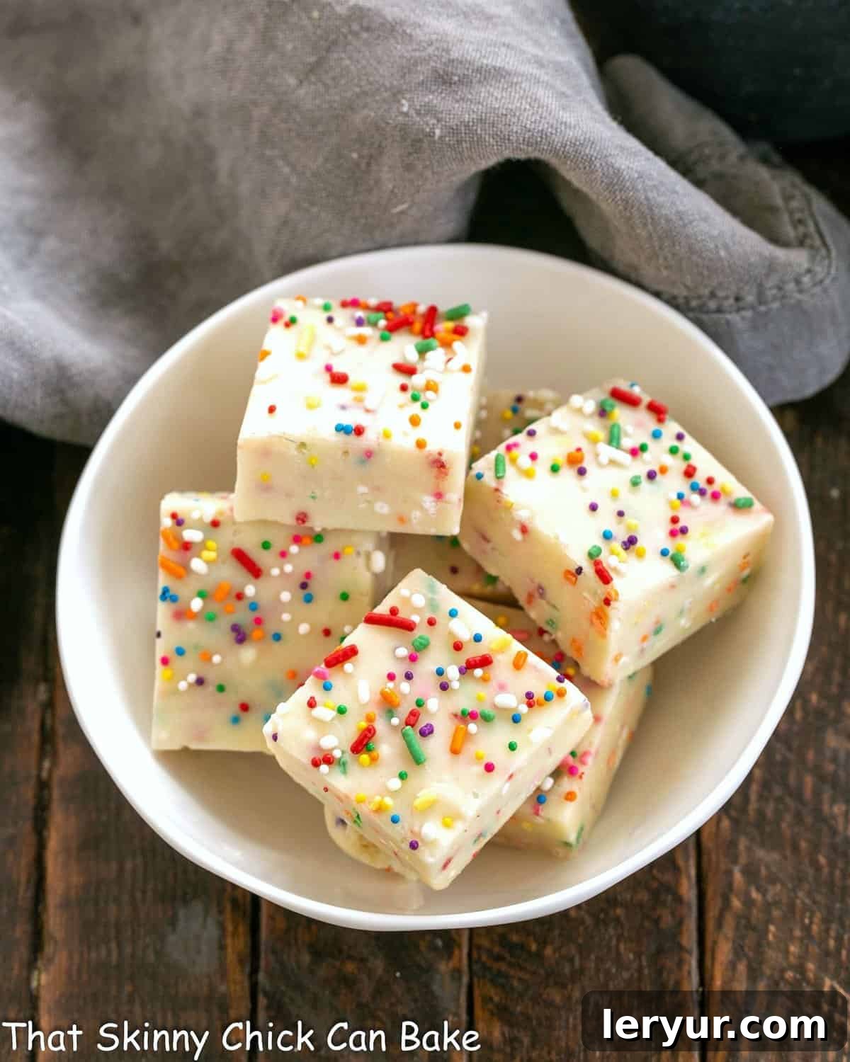 Confetti White Chocolate Fudge 2 Squares of cake batter fudge in a white bowl, glistening with sprinkles.