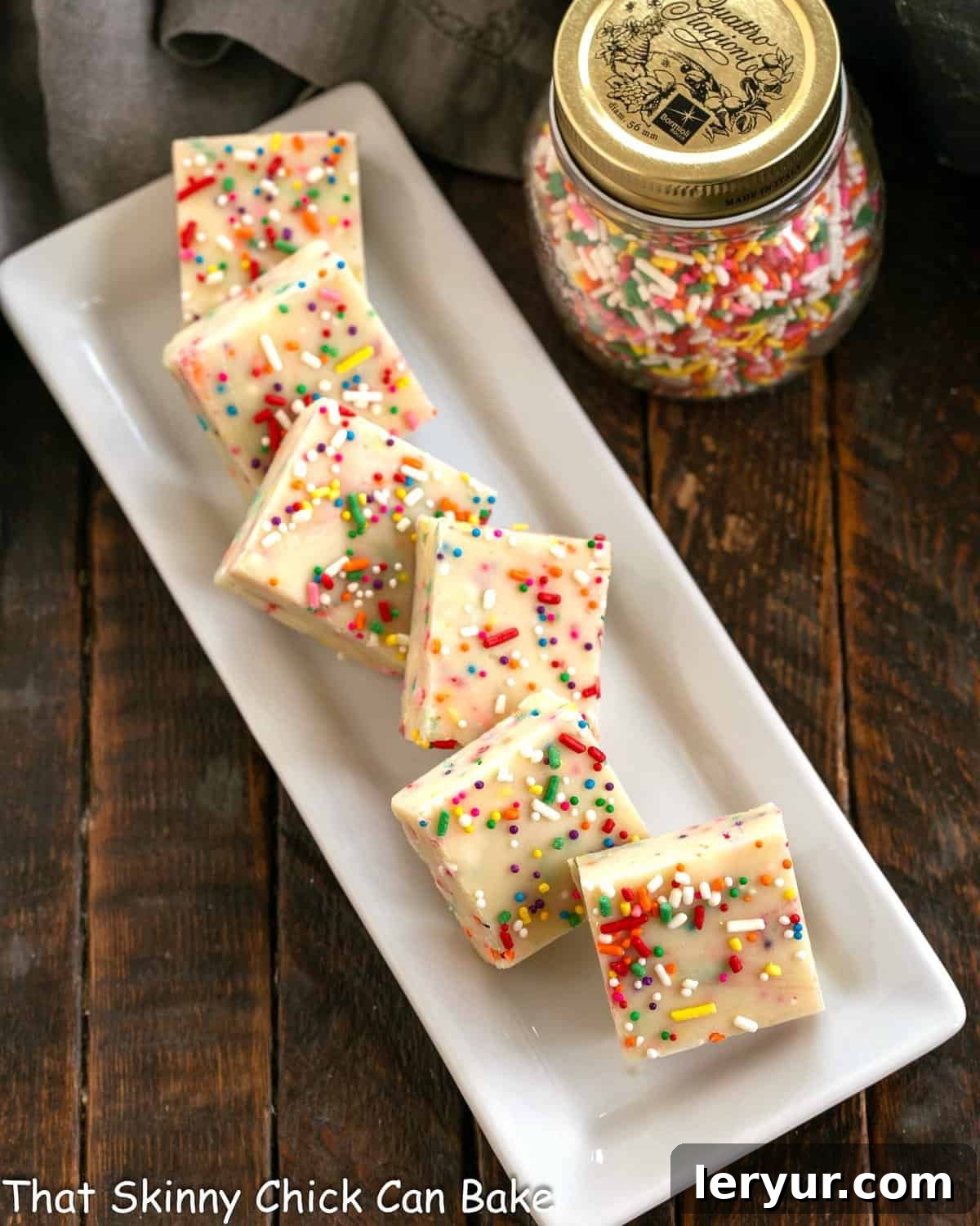 Confetti White Chocolate Fudge 4 Perfectly cut squares of cake batter fudge on a pristine white ceramic tray, ready to be enjoyed.