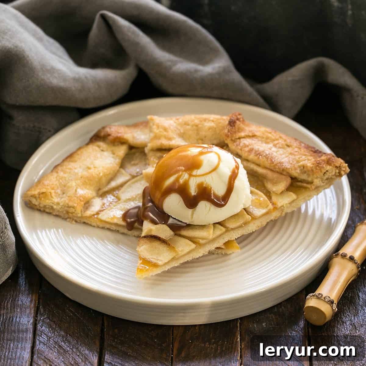 Two slices of apple crostata with a scoop of vanilla ice cream and caramel sauce.