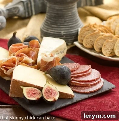Crafting an Easy Cheese Board 2 A slate cheese board topped with an exquisite selection of meats, various cheeses, and fresh garnishes on a vibrant red napkin.