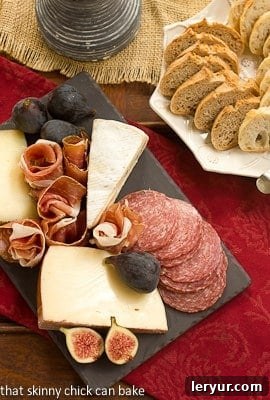 Crafting an Easy Cheese Board 3 Overhead view of a beautifully arranged meat and cheese tray next to a plate of artisan bread, showcasing a variety of textures and colors.