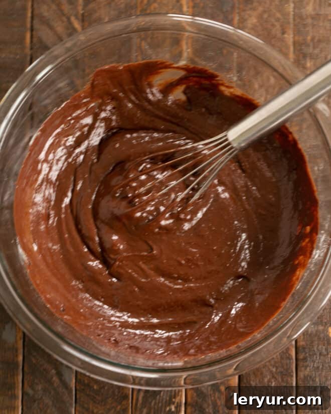 Ultimate Peanut Butter Fudge Swirl Cookies 6 Step 3: Gradually combining the melted chocolate mixture with the egg and sugar mixture.