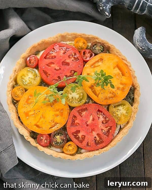 Overhead perspective of a beautifully arranged Fresh Tomato Tart on a rustic serving plate, adorned with fresh herbs, ready to be sliced.