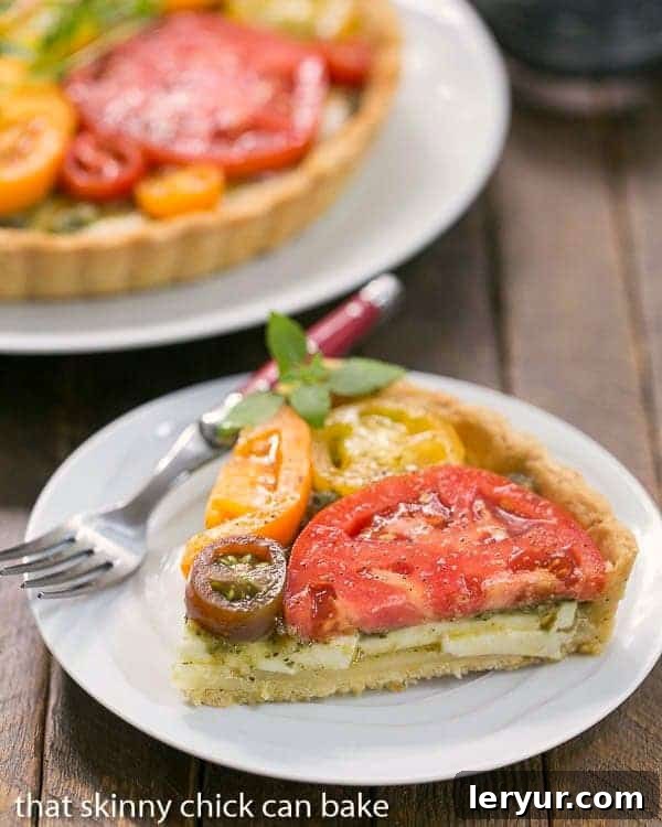 A delectable slice of Fresh Tomato Tart resting on a small white plate, accompanied by a fork with a vibrant red handle.