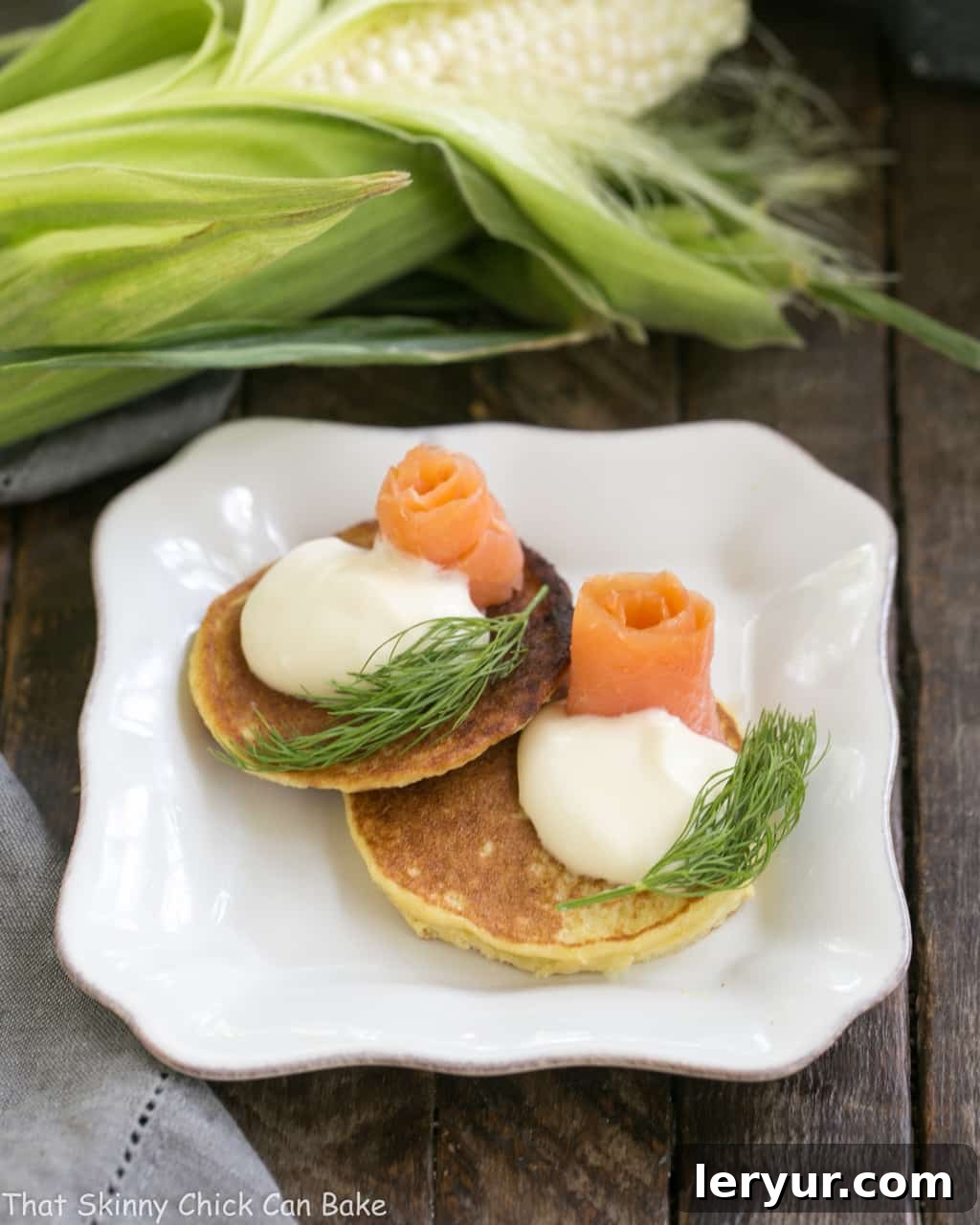 Fresh Corn Pancakes on a square plate topped with salmon and dill.
