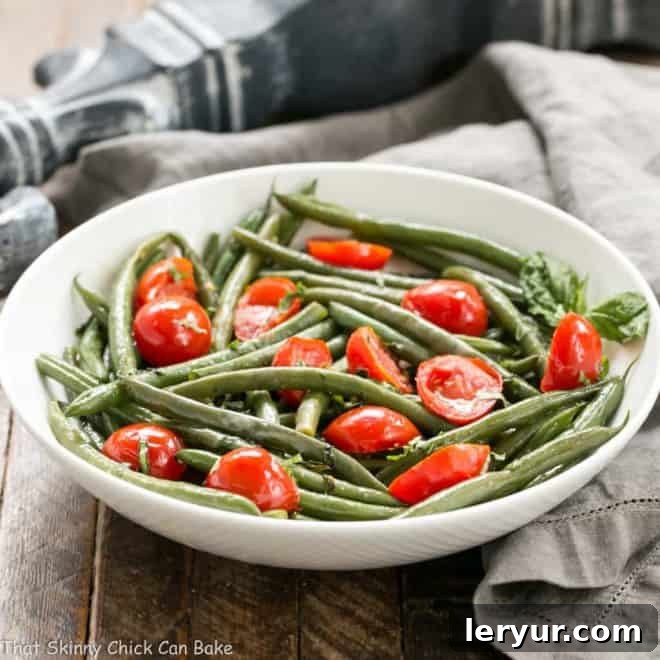 Sauteed Green Beans with tomatoes - An easy, delicious green bean recipe! Haricot Verts with Grape Tomatoes in a white ceramic bowl with a garnish of fresh basil