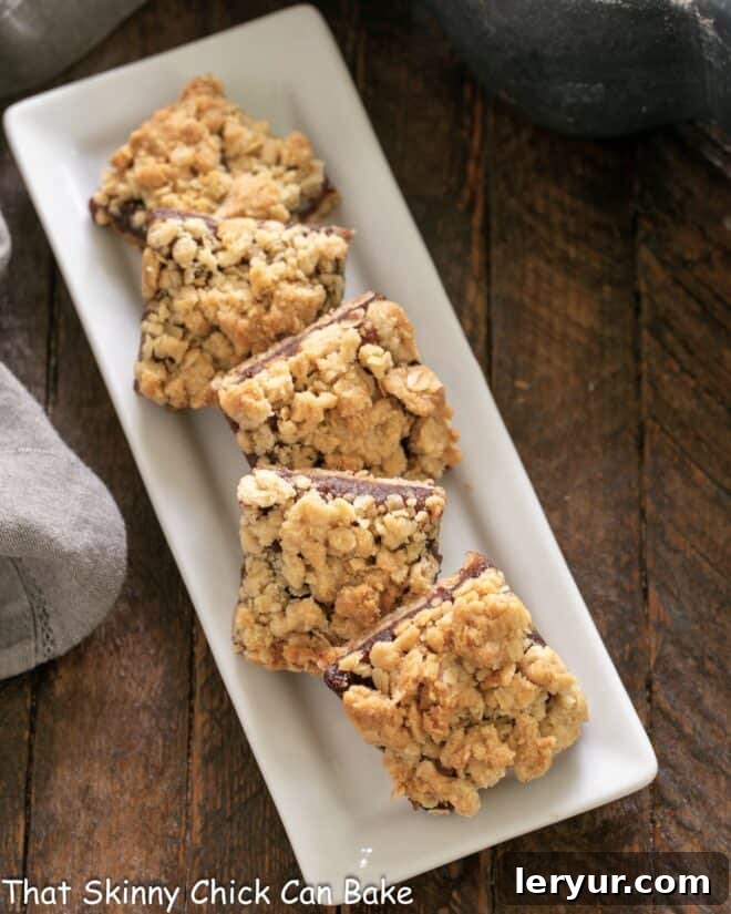 Freshly baked streusel-topped date bars arranged neatly on a white ceramic serving tray, ready to be enjoyed.