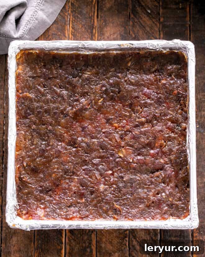 A layer of smooth, dark date topping spread evenly over the pre-baked crumb crust in a baking pan.