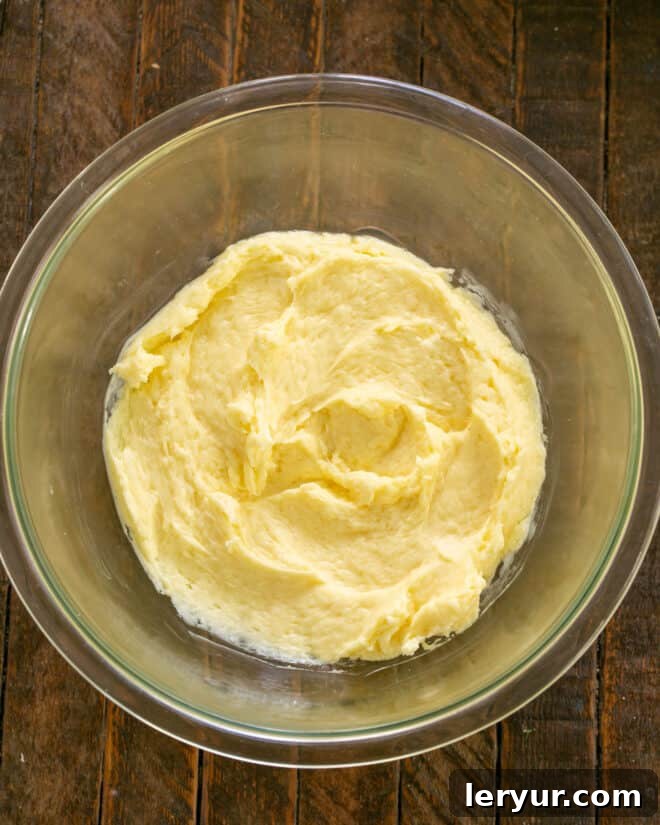 Sunny Lemon Impressions 5 Egg added to butter and sugar in a mixing bowl.