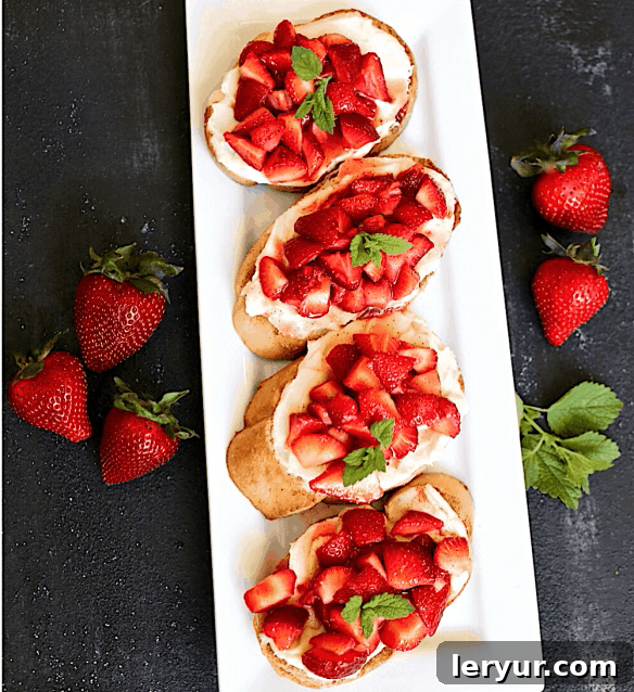 Sweet Balsamic Strawberry Bites 2 Overhead view of a white tray adorned with meticulously arranged strawberry crostini, featuring vibrant red berries and creamy white mascarpone