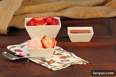 Strawberry Mascarpone Bliss 2 A small white bowl filled with creamy strawberry mascarpone ice cream, garnished with fresh strawberry slices and a spoon