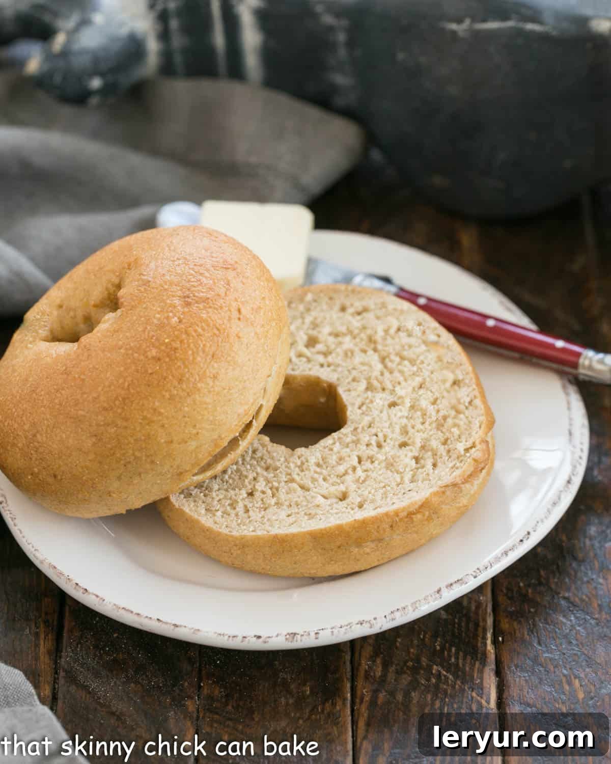 A perfectly sliced whole wheat bagel on a round white plate, ready to be topped.