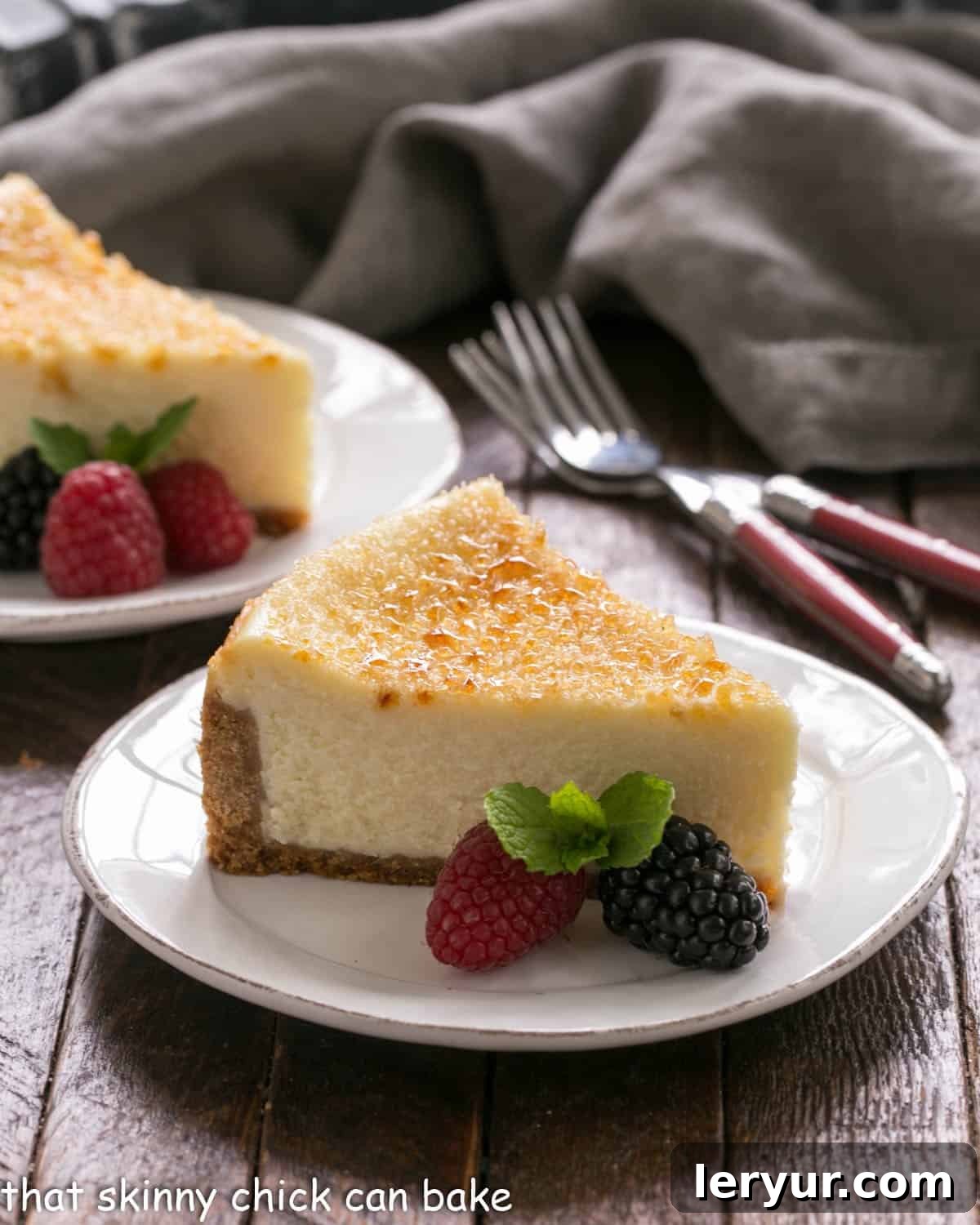Crème Brûlée Cheesecake - a cross between 2 delicious desserts for a magnificent cheesecake recipe Two slices of creme brulee cheesecake on white plates with berry garnish.