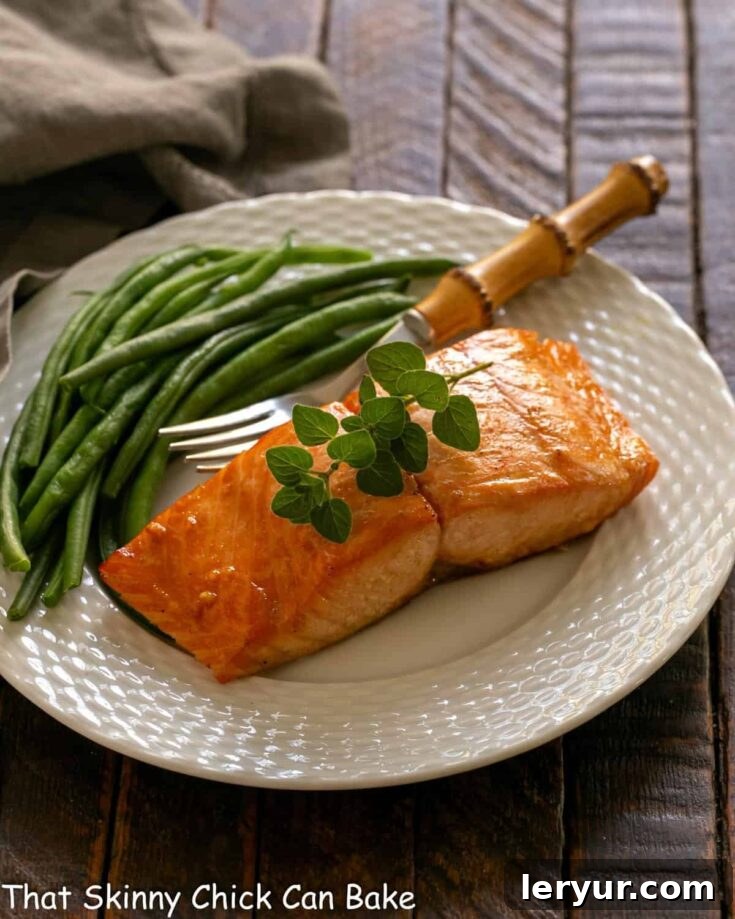Marinated salmon for two on a white plate with a fork and green beans, a mouthwatering view.