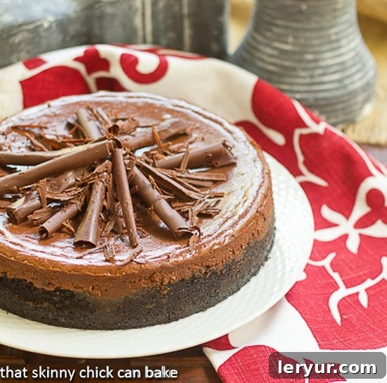 A whole Double Chocolate Cheesecake, elegantly presented on a round white serving plate, adorned with a generous layer of chocolate curls, showcasing its irresistible appeal.