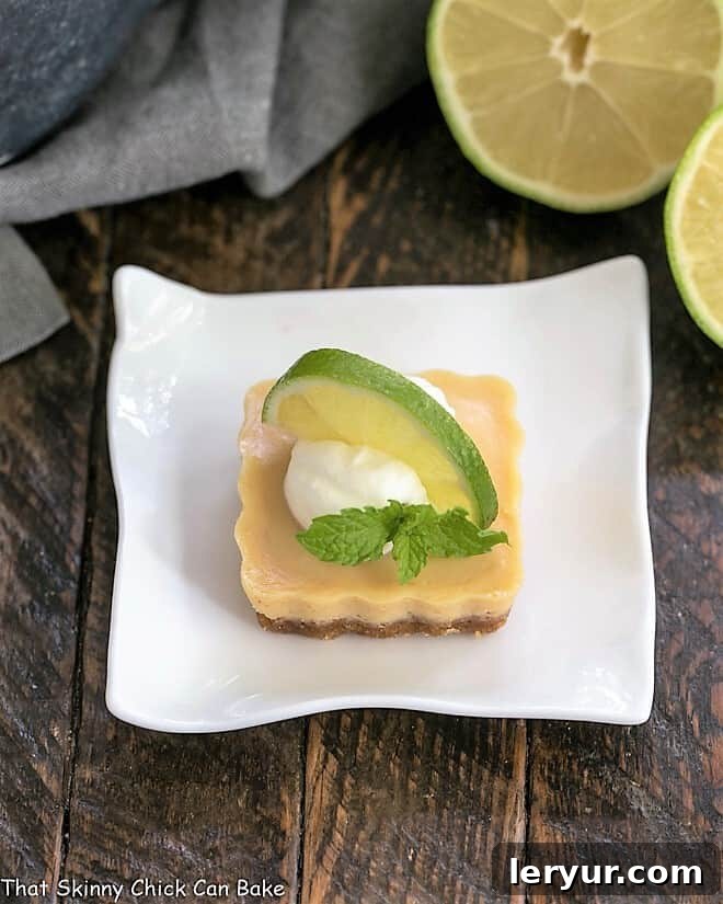 Key Lime Tartlet on a white plate with a dollop of whipped cream and a slice of lime, ready to be enjoyed.