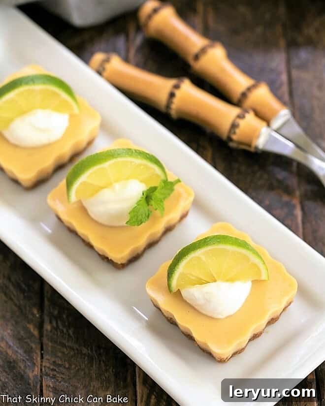 Overhead view of several Key Lime Tarts arranged neatly on a white ceramic tray, highlighting their uniform shape and appealing texture.