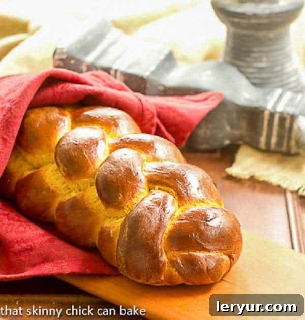 Pumpkin Challah: The Ultimate Fall Braided Bread for Your Table A beautifully braided Pumpkin Challah loaf, still warm, wrapped in a red linen napkin on a rustic wooden cutting board, ready to be sliced and served.