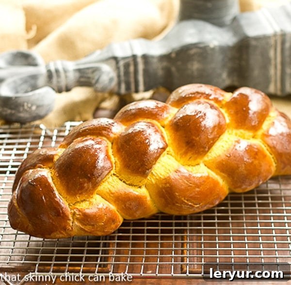 Golden Pumpkin Challah 3 A delicious loaf of pumpkin challah, cooling on a rack, with a golden-brown crust and a perfectly braided shape, embodying the warmth of fall.