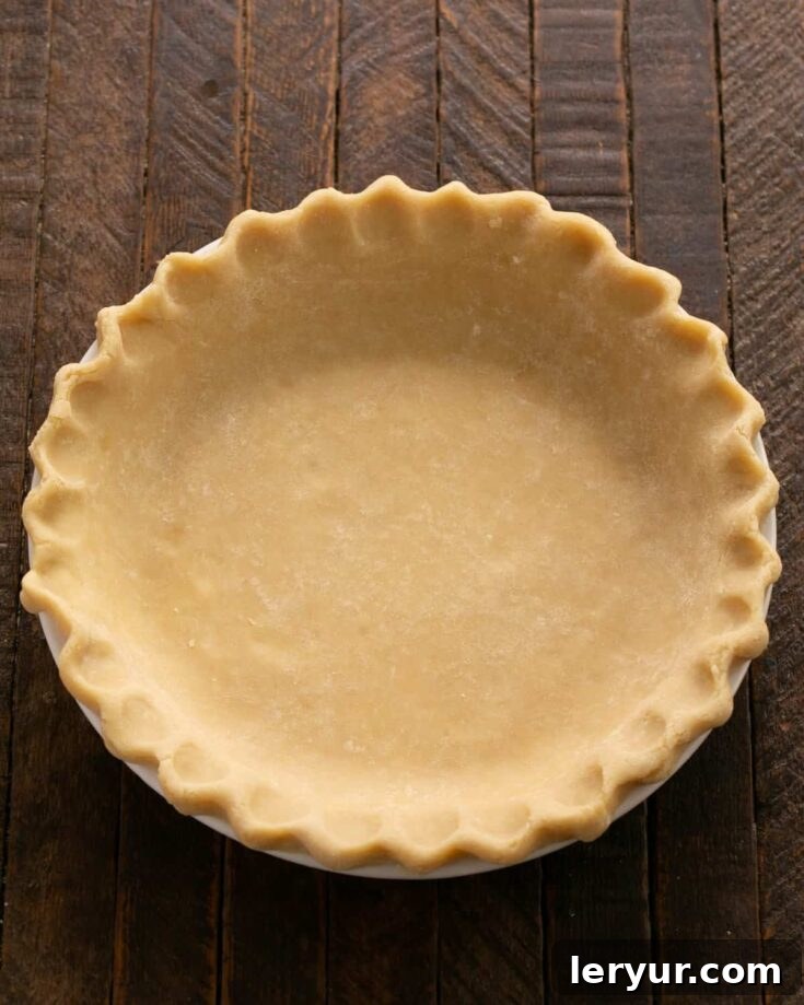 Crimped pie crust in a pie plate, ready for filling. The perfectly crimped edges showcase the meticulous care in preparing this homemade pie crust.