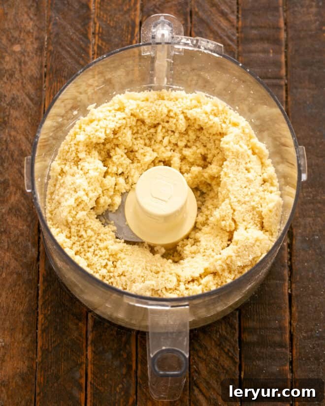 Ice water being drizzled into the food processor while pulsing.