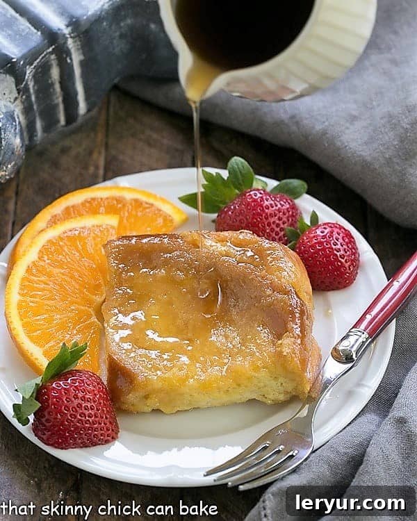 Overnight Crème Brûlée French Toast Bake 2 Golden maple syrup being poured over a thick slice of Crème Brûlée French Toast, showcasing its beautiful caramelized crust and soft, absorbent texture.