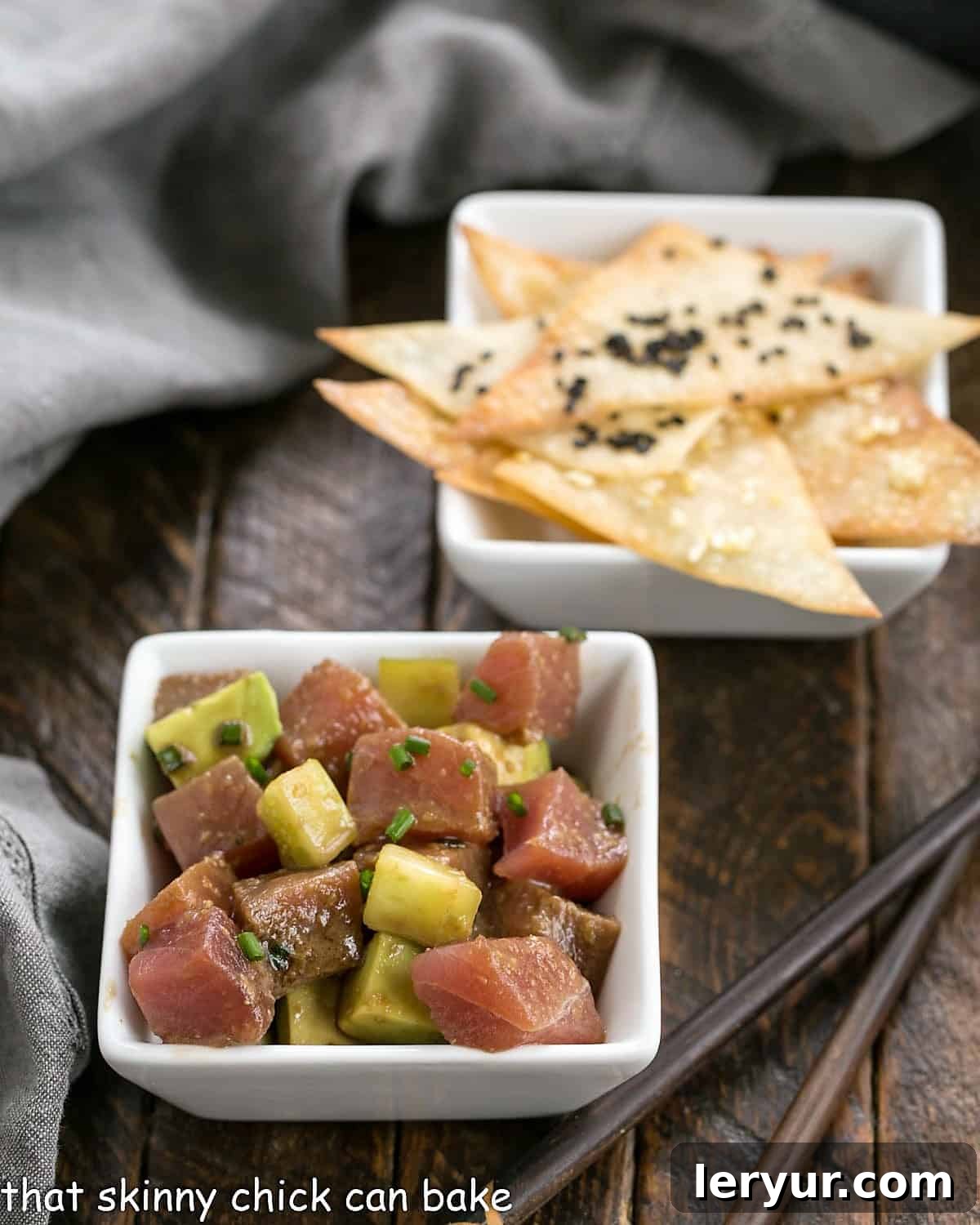 Square bowl filled with vibrant Ahi Tuna Tartare and avocado, accompanied by crispy wonton chips, artfully arranged for a delightful appetizer.