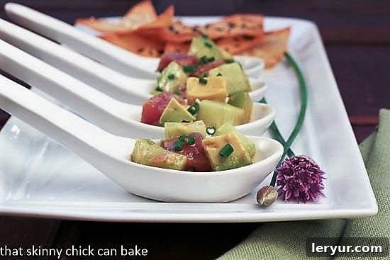 Individual servings of fresh Tuna Tartare with avocado, artfully presented in Asian-style ceramic spoons on a pristine white tray.