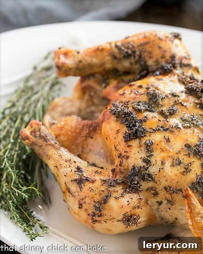 Oven Roasted Chicken- A slashing technique and a few ingredients make for a succulent entree! A perfectly cooked Whole Roasted Chicken, beautifully presented on an oval serving platter and garnished with fresh thyme sprigs.